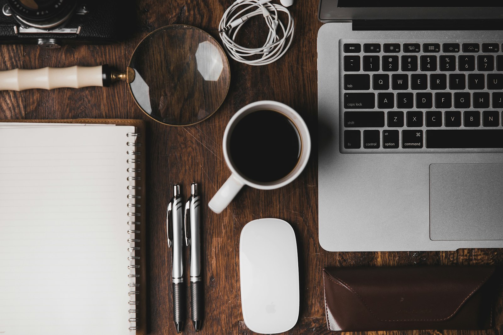 Arbeidsbord med laptop, notatbok og kaffe